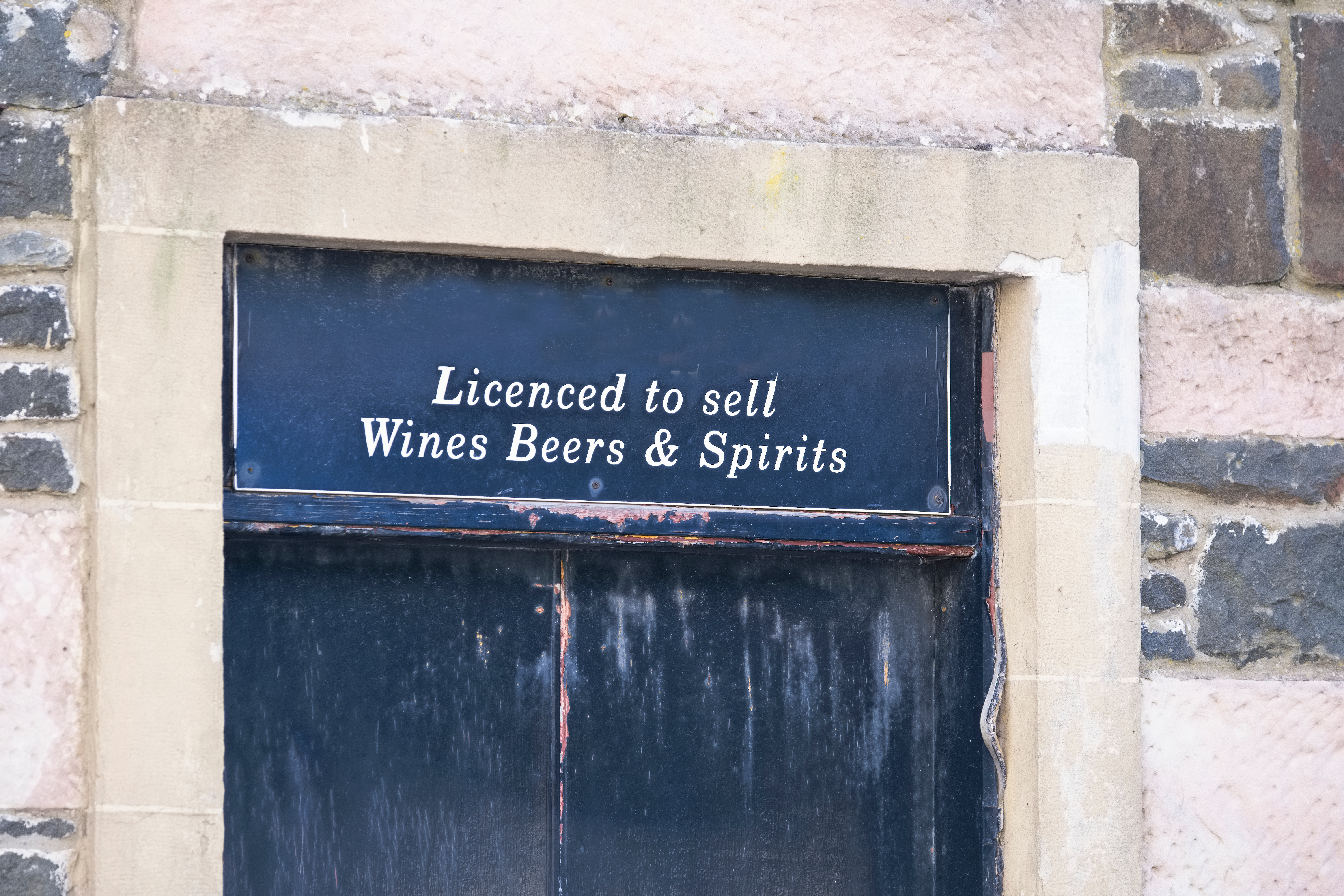 A door with a sign that says Licenced to sell Wine Beers & Spirits